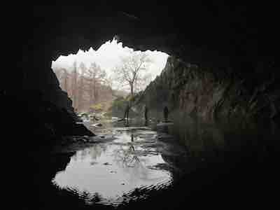 Walking group posing on stepping stones in Rydal Cave